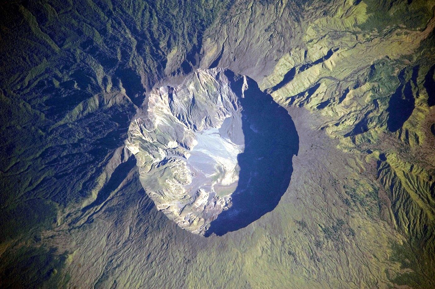 volcano erupting with ash cloud over island coast